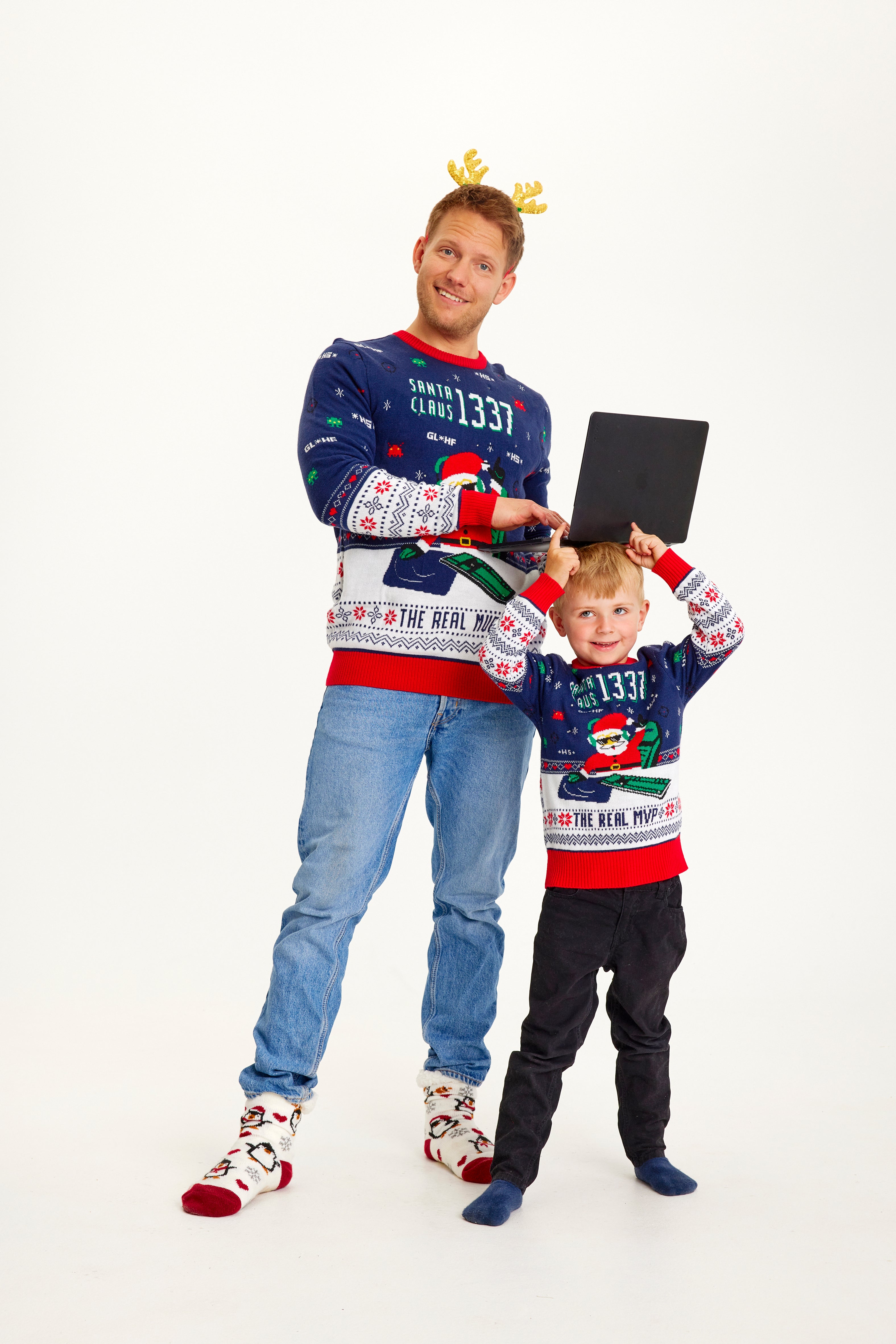 En smilende mand og et barn poserer sammen i matchende blå julesweatre.